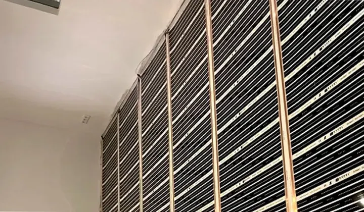 Rows of black carbon heating film fixed across a ceiling before the plasterboard goes on