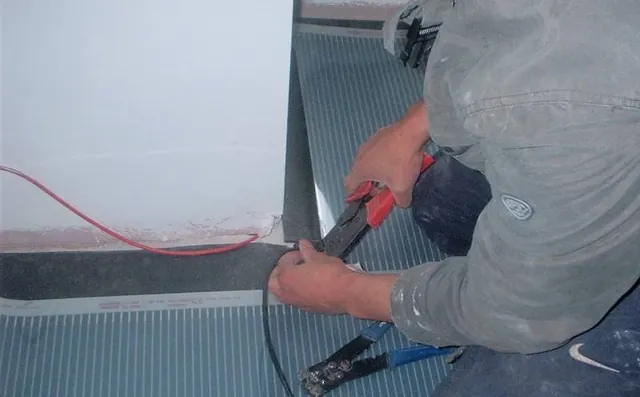Carbon heating film laid across a floor while its connections are made