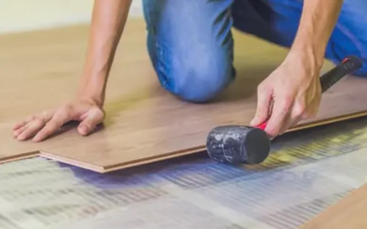 Laminate boards being laid over thin heating film on a floor